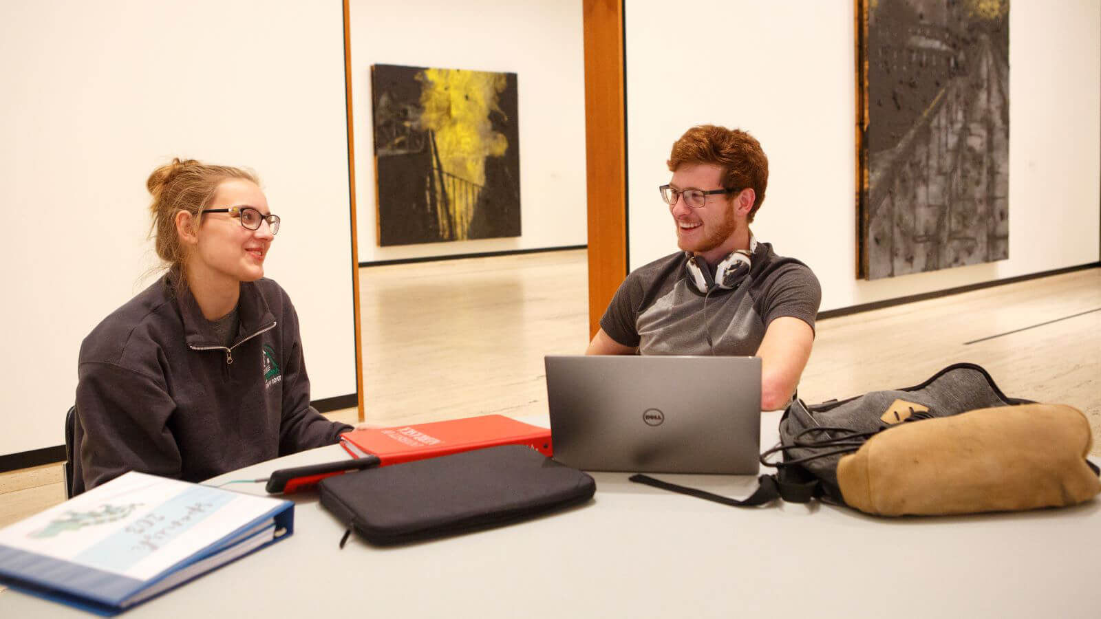 Philosophy students talking in meeting space with art on walls